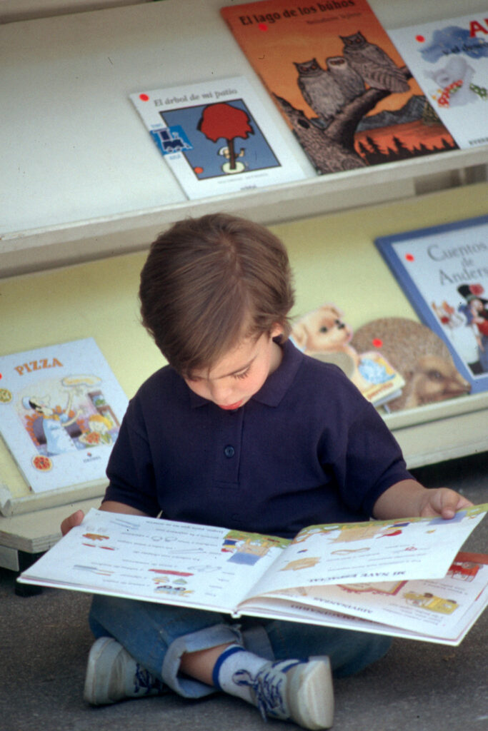 Jongen leest boek in bibliotheek